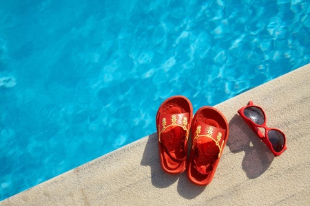 Colored flipflops  and sunglasses by the swimming poolの写真素材
