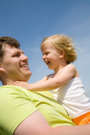 Happy father has a good summer time with his little daughter background on the blue skyの写真素材