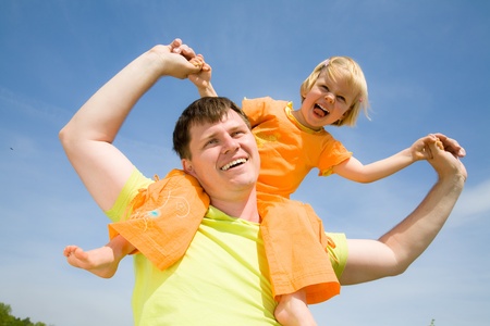 Happy father has a good summer time with his little daughter background on the blue skyの写真素材
