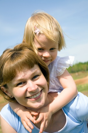 Happy mother has a good summer time with her little daughter background on the blue sky の写真素材