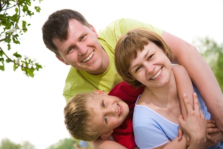 happy family portrait of attractive couple with their young son background on the blue skyの写真素材
