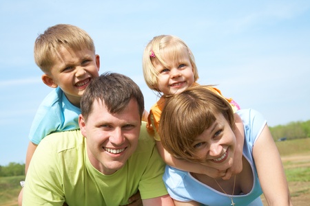 family lifestyle portrait of a mum and dad with their children having good time on the green grassの写真素材