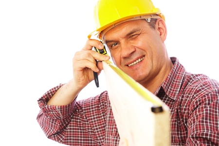 handsome skilful carpenter measures the board isolated on white backgroundの写真素材