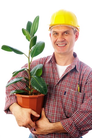 handsome man-builder holding a green plant in a potの写真素材