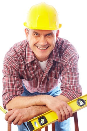 vertical portrait of a smiling handsome man-builder in helmet with tool on a white background の写真素材