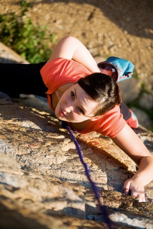 The beautiful girl is engaged in rock-climbing on a vertical rockの写真素材