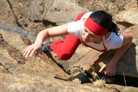 The beautiful girl is engaged in rock-climbing on a vertical rockの写真素材