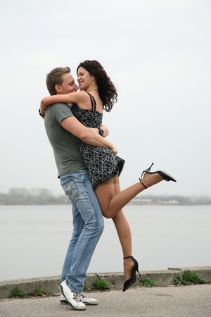 A pair of beautiful young people embracing and kissing on the embankment of the riverの写真素材