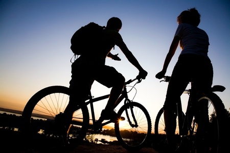 Beautiful Couple on bicycles on the brink of a rock and look afar from rock breakage の写真素材