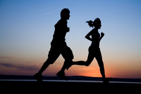 The man and the woman run together on a sunset on lake coastの写真素材