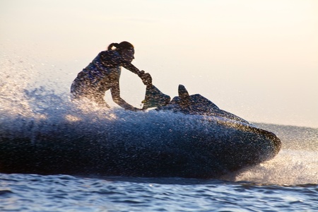 beautiful girl riding her jet skis in the sea at sunset. silluetの写真素材