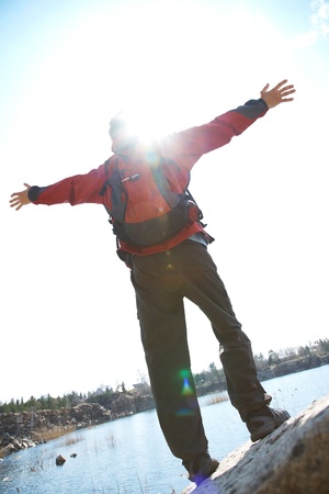 Happy man hiker holding his arms in the air in a feeling of success having reached the summitの写真素材