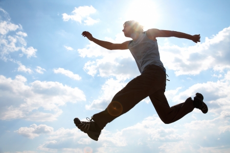 Young man is jumping against cloudy sky  Use it for lifestyle conceptsの写真素材