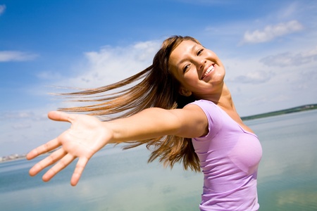 beautiful young woman opened her hands with delight at the blue skyの写真素材