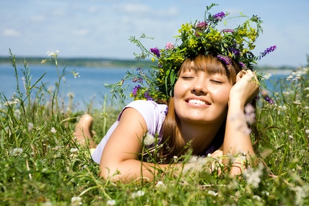 beautiful girl in  wreath of flowers lay in  meadow on sunny dayの写真素材
