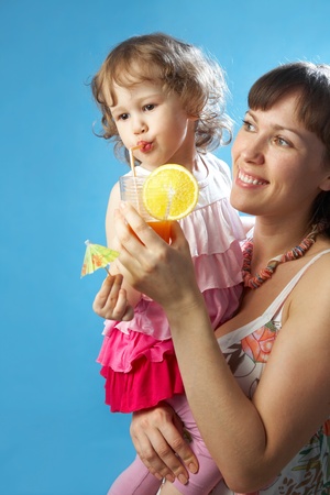 Portrait of young mother with her daughter on the blue backgroundの写真素材