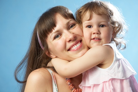 Portrait of young mother with her daughter on the blue backgroundの写真素材
