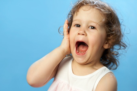 Portrait of funny lovely little girl on the blue backgroundの写真素材