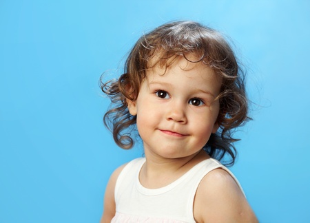 Portrait of funny lovely little girl on the blue backgroundの写真素材