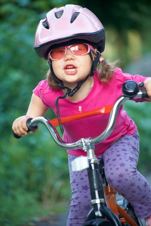 Portrait of a little girl on a bicycle in summer park outdoorsの写真素材