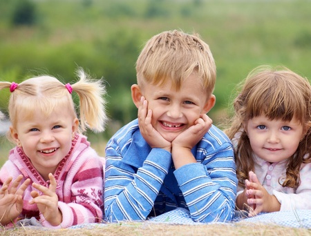 portrait of  group of children happily laughing and lying on the grassの写真素材