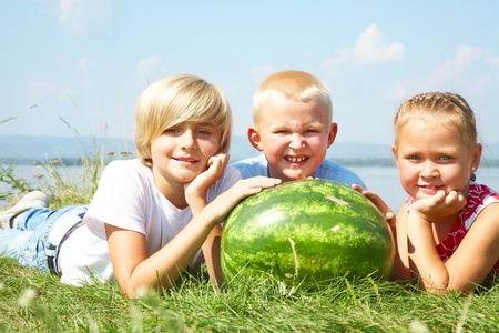 Children lying in grass with  red watermelon の写真素材