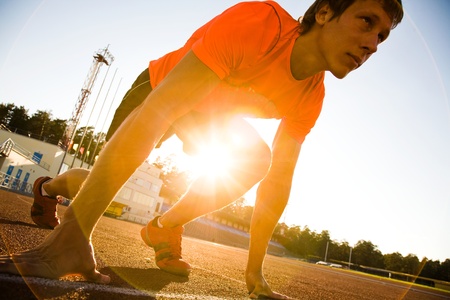 young muscular athlete is at the start of the treadmill at the stadiumの写真素材