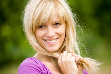 portrait of young beautiful woman with fair hair on  background  of green forestの写真素材