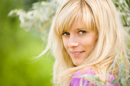 portrait of young beautiful woman with fair hair on  background  of green forestの写真素材