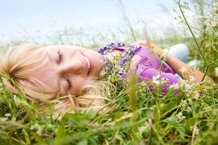 young beautiful woman with fair hair lying on the grassの写真素材