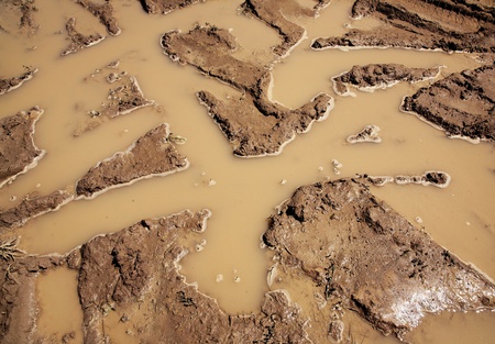 puddle on rural road in the form of  beautiful pattern of wheel cars tracks filled with waterの写真素材