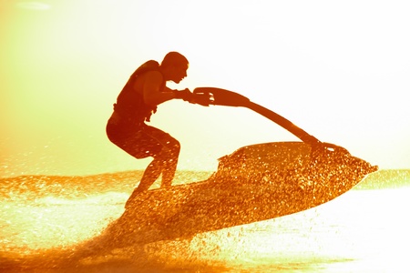 strong man drive on the jetski above the water at sunset .silhouette. spray.の写真素材