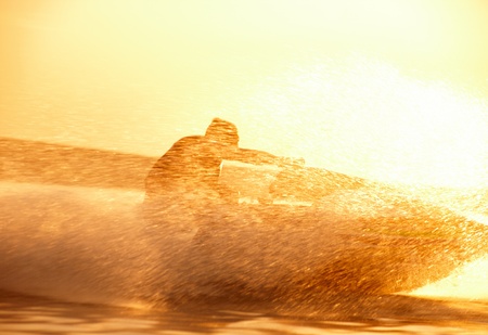 strong man jumps on the jetski above the water at sunset .silhouette spray.の写真素材