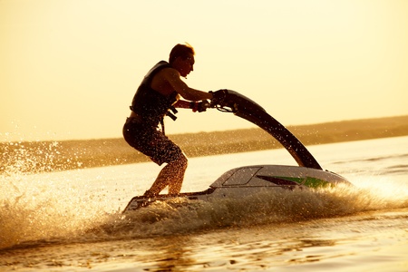 strong man drive on the jetski above the water at sunset .silluet. sprayの写真素材