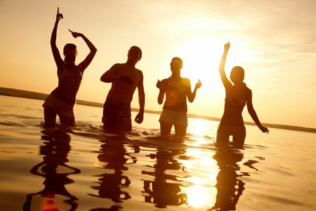 group of happy young people dancing at the beach on  beautiful summer sunsetの写真素材