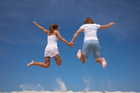 Photo of happy couple in jump with bright blue sky at backgroundの写真素材