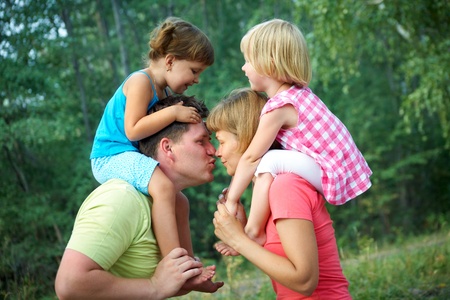  mum and dad kiss  with their children  in the green  parkの写真素材