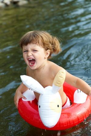  little girl swims in  sea in an red  life preserverの写真素材