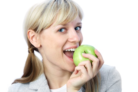 Portrait of smiling blonde girl with green apple on the white backgroundの写真素材