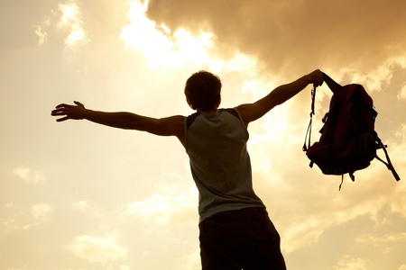 Happy man hiker holding his arms in the air in a feeling of success having reached the summitの写真素材