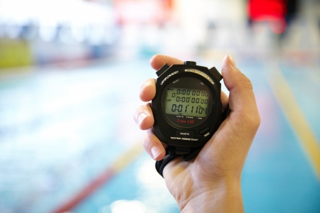 hand of coach with a stopwatch during competitions in the swimming poolの写真素材