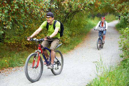 Couple riding bicycle in parkの写真素材