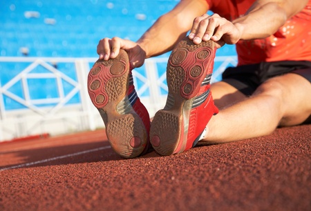 young athlete sits on the treadmill stadium legs spread. Failure.