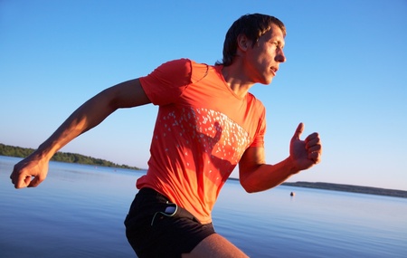 Young man running along the seashore at sunset