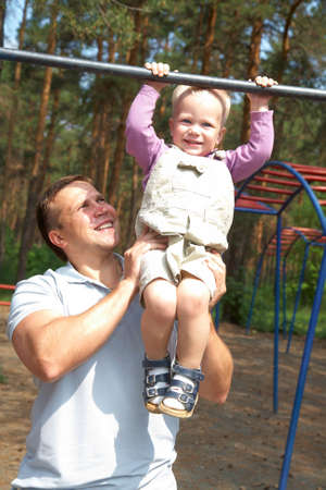 Dad and his little son do exercises on the crossbar in the park