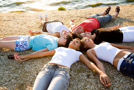 group of young people lie on the beach holding hands enjoying relaxの写真素材