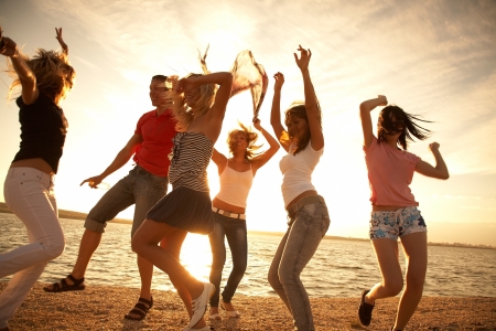 group of happy young people dancing at the beach on  beautiful summer sunsetの写真素材