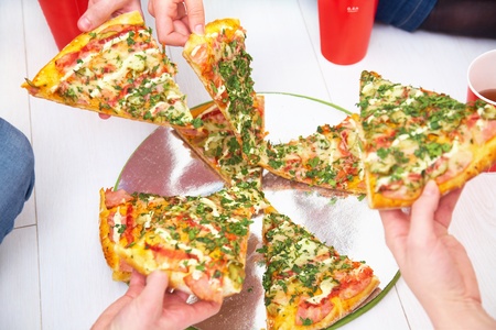 slices of pizza is lifted from human handsの写真素材