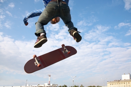 Skater jumps high in air on background blue sky の写真素材