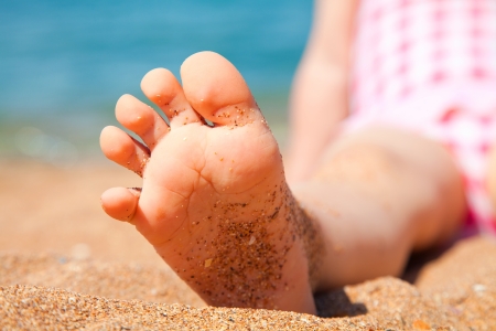 child's foot is close to the sandy beach of the seaside resortの写真素材